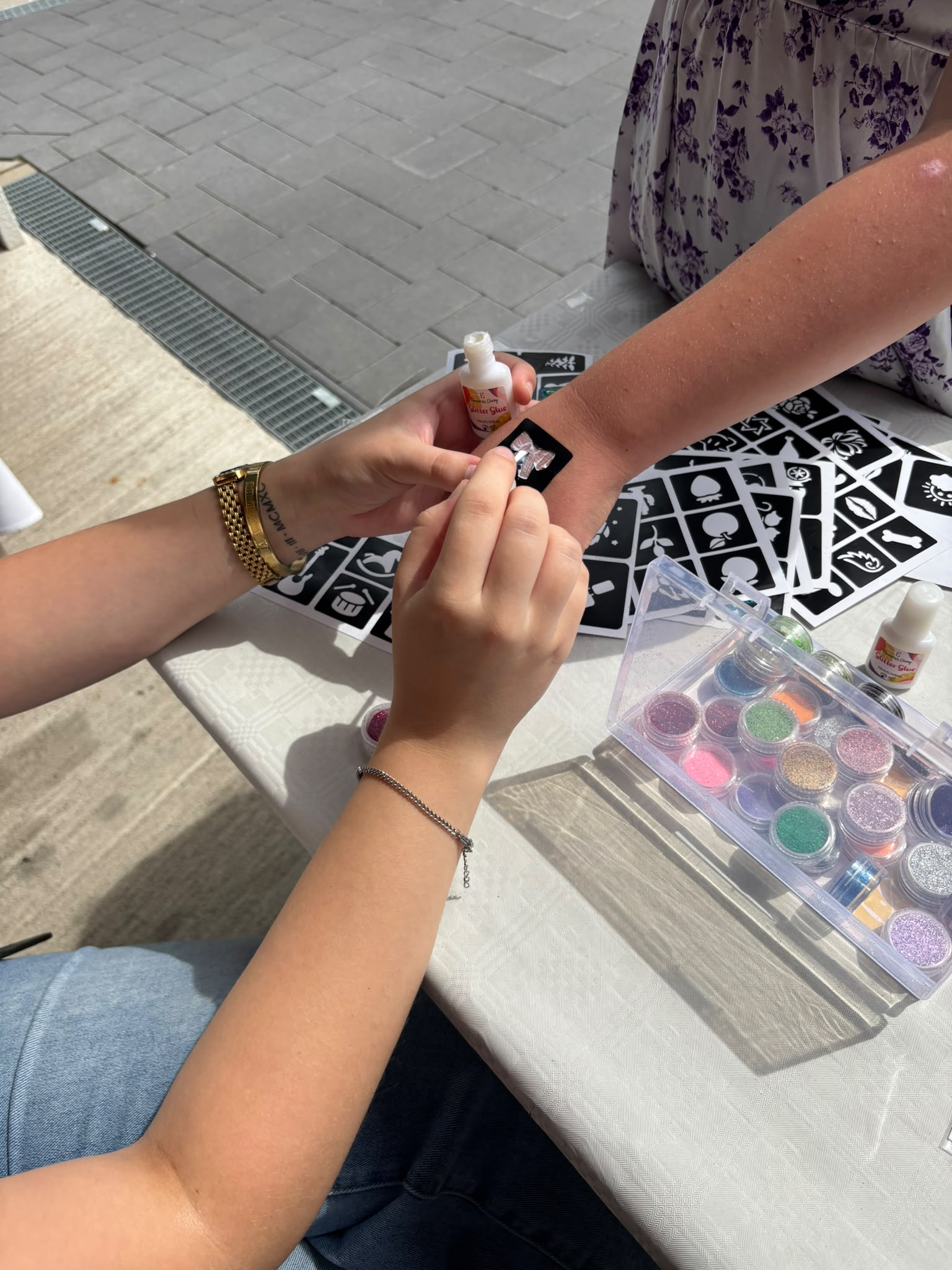 Lea gestaltet behutsam ein Glitzermotiv auf einem Arm